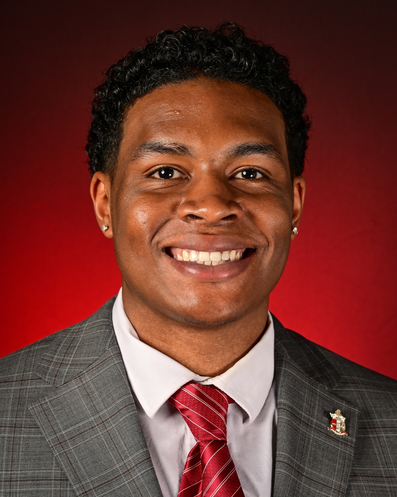 Xavier Harris, founder of Becoming Excellence, in a gray suit and red tie